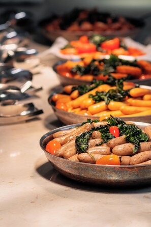 A buffet table with various dishes including sausages, carrots, and greens. - Grand Mercure Dalat (Lam Vien - Da Lat)
