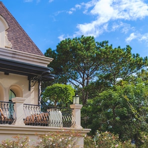 A building with a balcony, a lamp post, and a tree in the background. - Grand Mercure Dalat (Lam Vien - Da Lat)