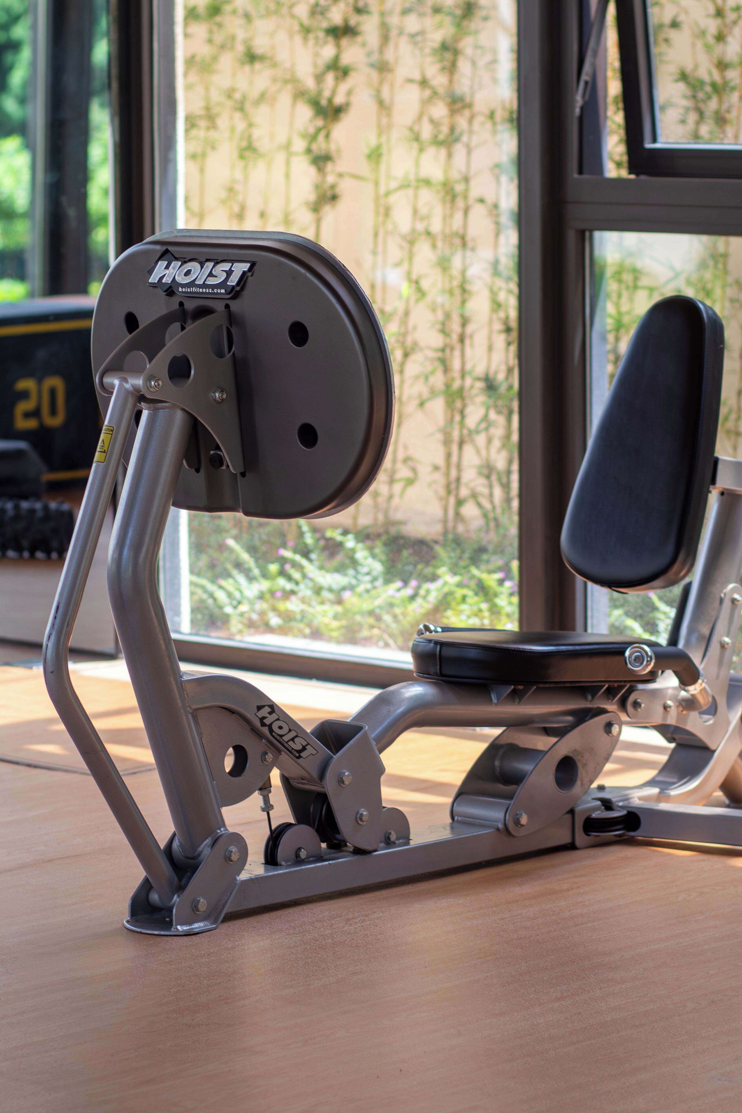 A stationary exercise machine with a brand label, positioned in front of a window with a view of greenery.