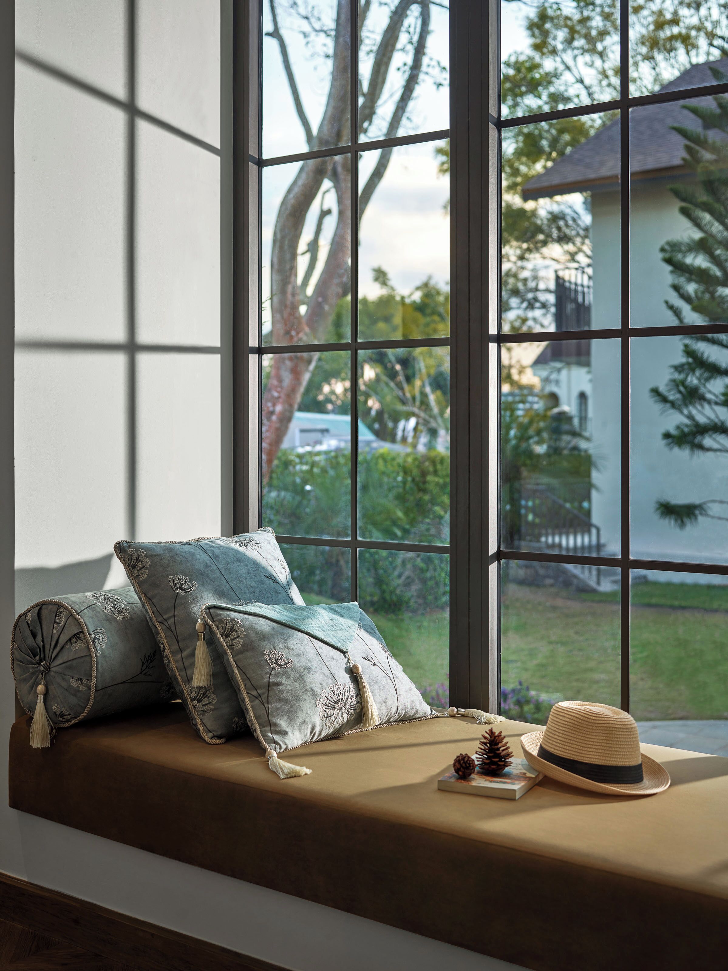 A window seat with cushions, a hat, and a book.