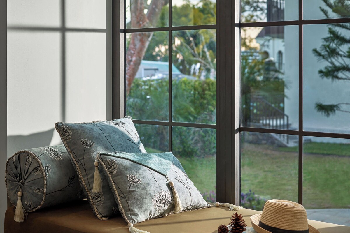 A window seat with cushions, a hat, and a book.