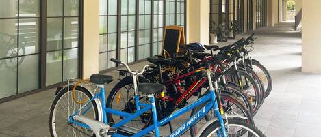 A hallway with bicycles parked along the wall, a signboard, and a staircase in the distance.