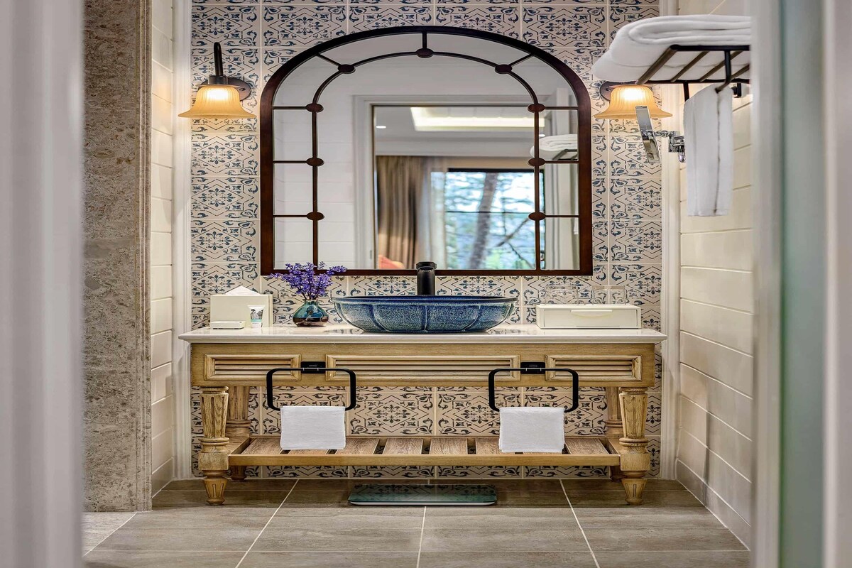 A bathroom with a large mirror, a blue basin, and a wooden vanity.