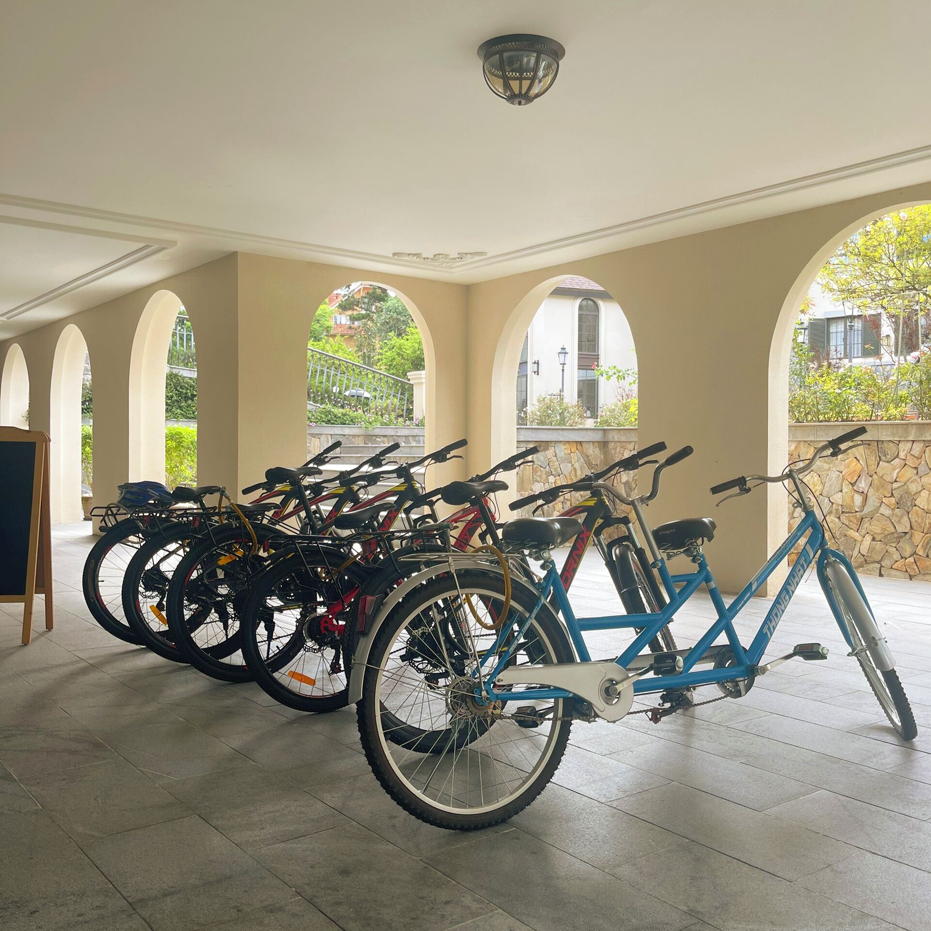 A covered bike parking area with multiple bicycles and a stone wall.
