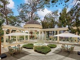 Un kiosque agrémenté d’une fontaine, entouré d’espaces de détente en plein air avec des parasols.