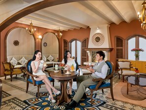A room with a round table, two sofas, and a fireplace. - Grand Mercure Dalat (Lam Vien - Da Lat)