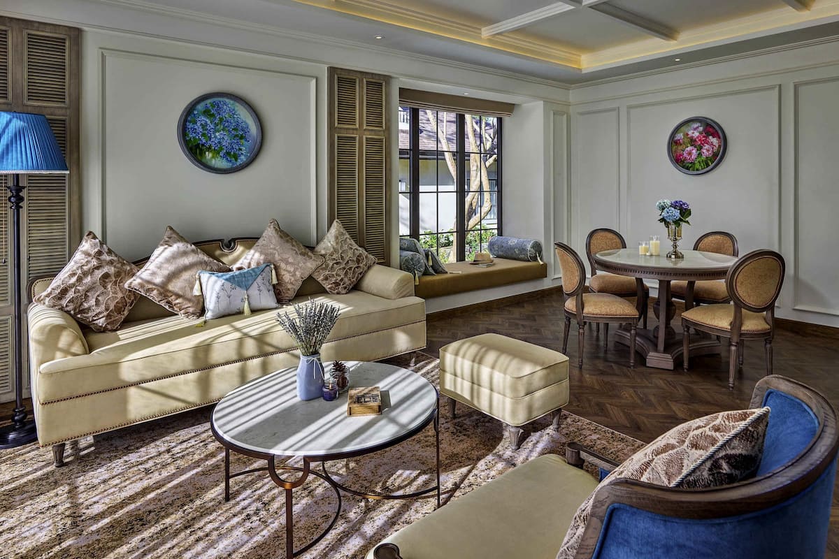 A living room with a sofa, ottoman, round coffee table, and a dining area with chairs and a table.