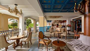 A hotel lobby with a bar area, seating arrangements, and a decorative ceiling.