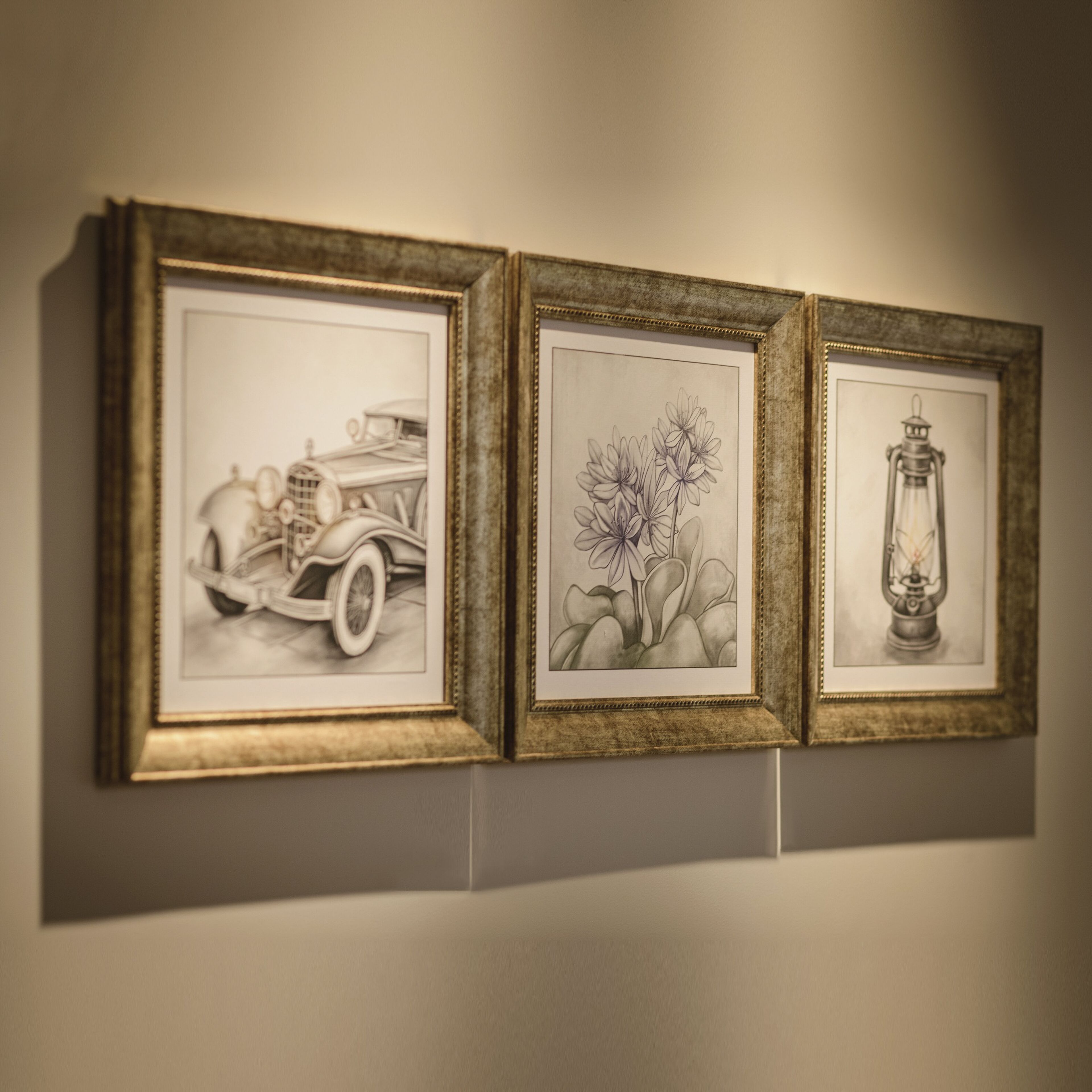Trois œuvres d’art encadrées sont accrochées au mur.