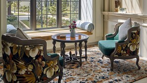 A room with a large window, a fireplace, and two upholstered chairs with floral upholstery. - Grand Mercure Dalat (Lam Vien - Da Lat)