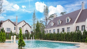 A large house with a swimming pool, surrounded by trees and a clear sky. - Grand Mercure Dalat (Lam Vien - Da Lat)
