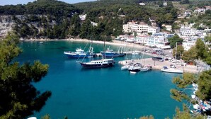 A coastal marina with several boats docked, surrounded by a town with buildings and greenery. - Ikion Eco Boutique Hotel (Alonissos)