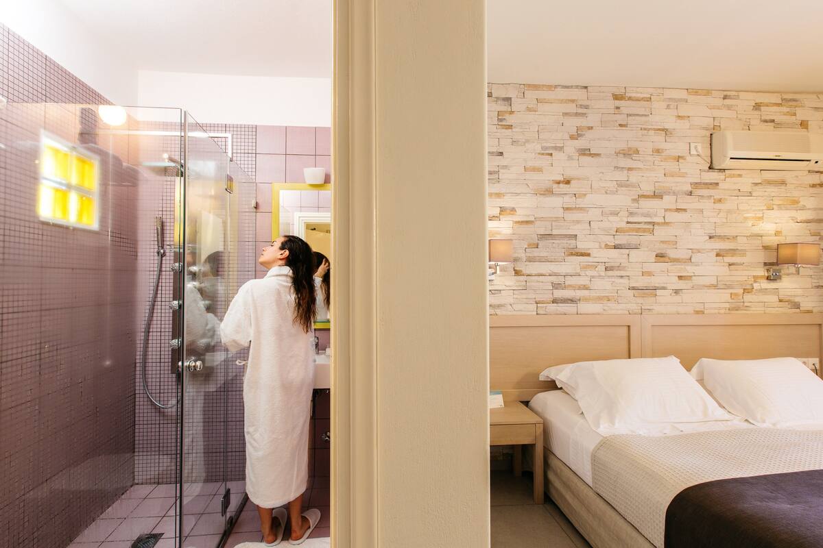 Een hotelkamer met een douche, een bed en een nachtkastje.