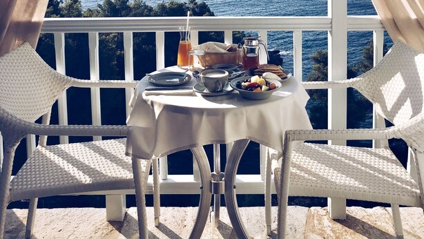 A balcony with a table set for breakfast overlooking the sea. - Ikion Eco Boutique Hotel (Alonissos)