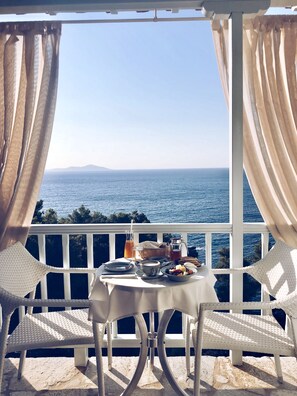 Un balcón con una mesa preparada para el desayuno con vista al mar.