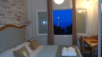 Une chambre d’hôtel avec un lit, une fenêtre avec des rideaux, une table et une chaise.