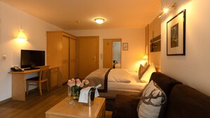 Una habitación de hotel con cama, sofá, escritorio con computadora y televisión.