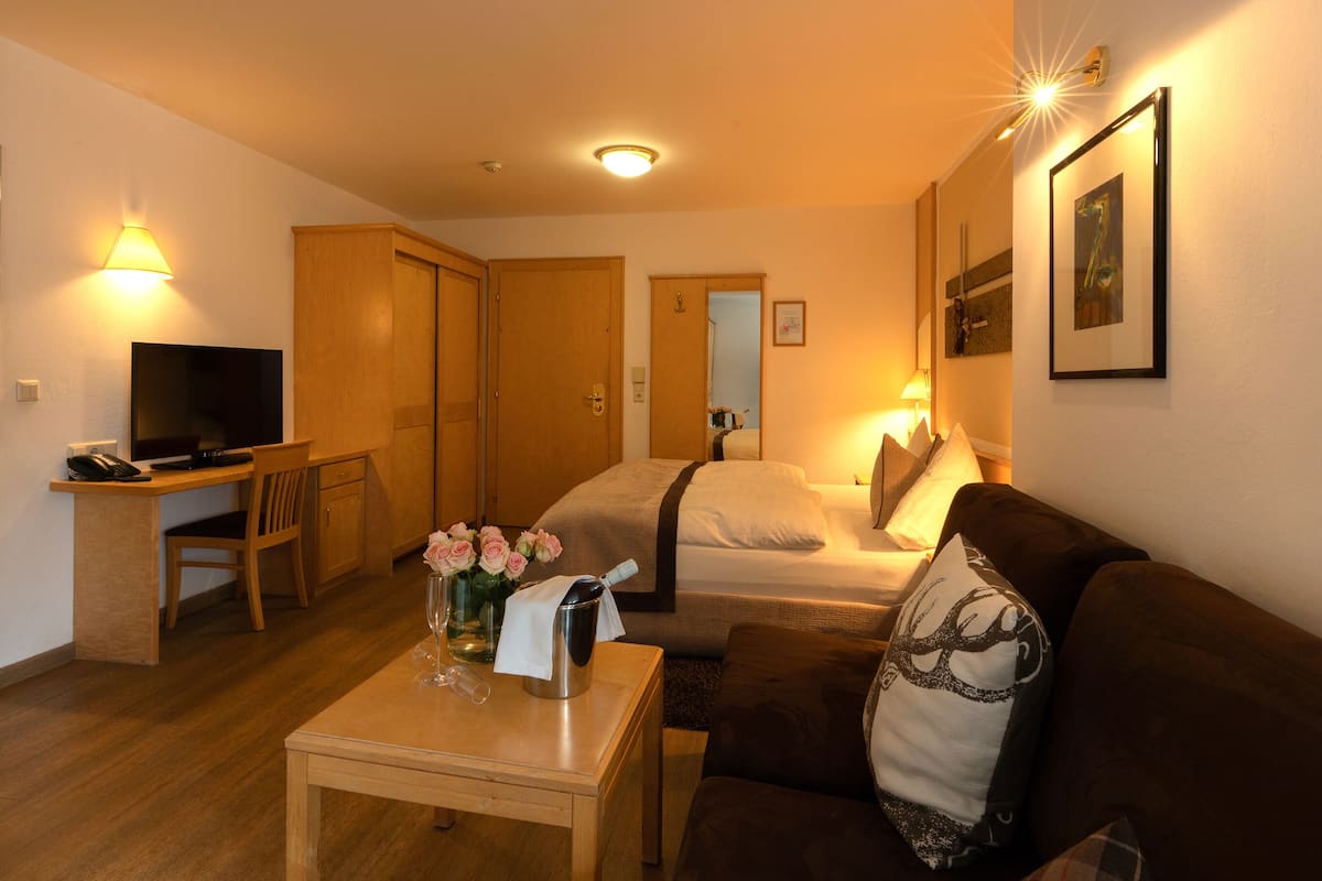 Una habitación de hotel con cama, sofá, escritorio con computadora y televisión.