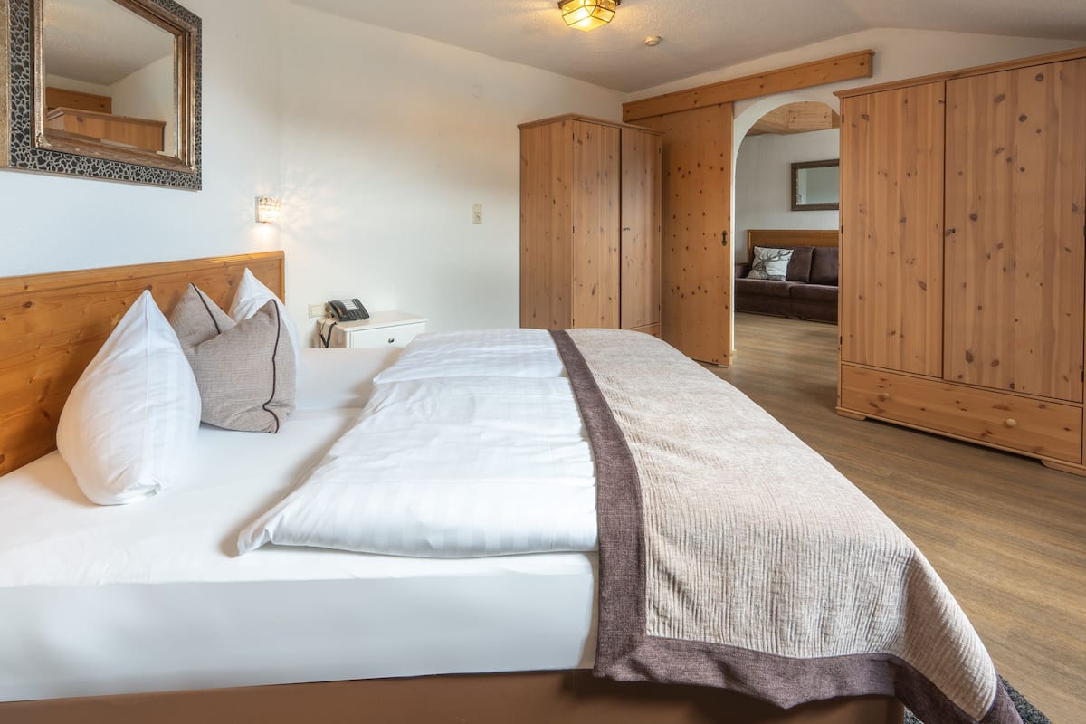Un dormitorio con una cama grande, un armario de madera y un espejo en la pared.