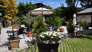 Un espacio al aire libre con mesas, sillas, un pabellón y plantas en macetas.