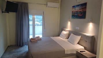 Habitación de hotel con cama, televisión montada en la pared, un cuadro y vistas de edificios a través de la ventana.