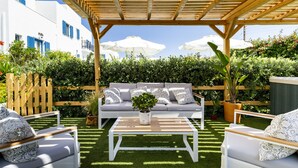 A covered outdoor seating area with a wooden pergola, a white sofa, and two white armchairs. - Ikaros Studios & Apartments (Naxos)