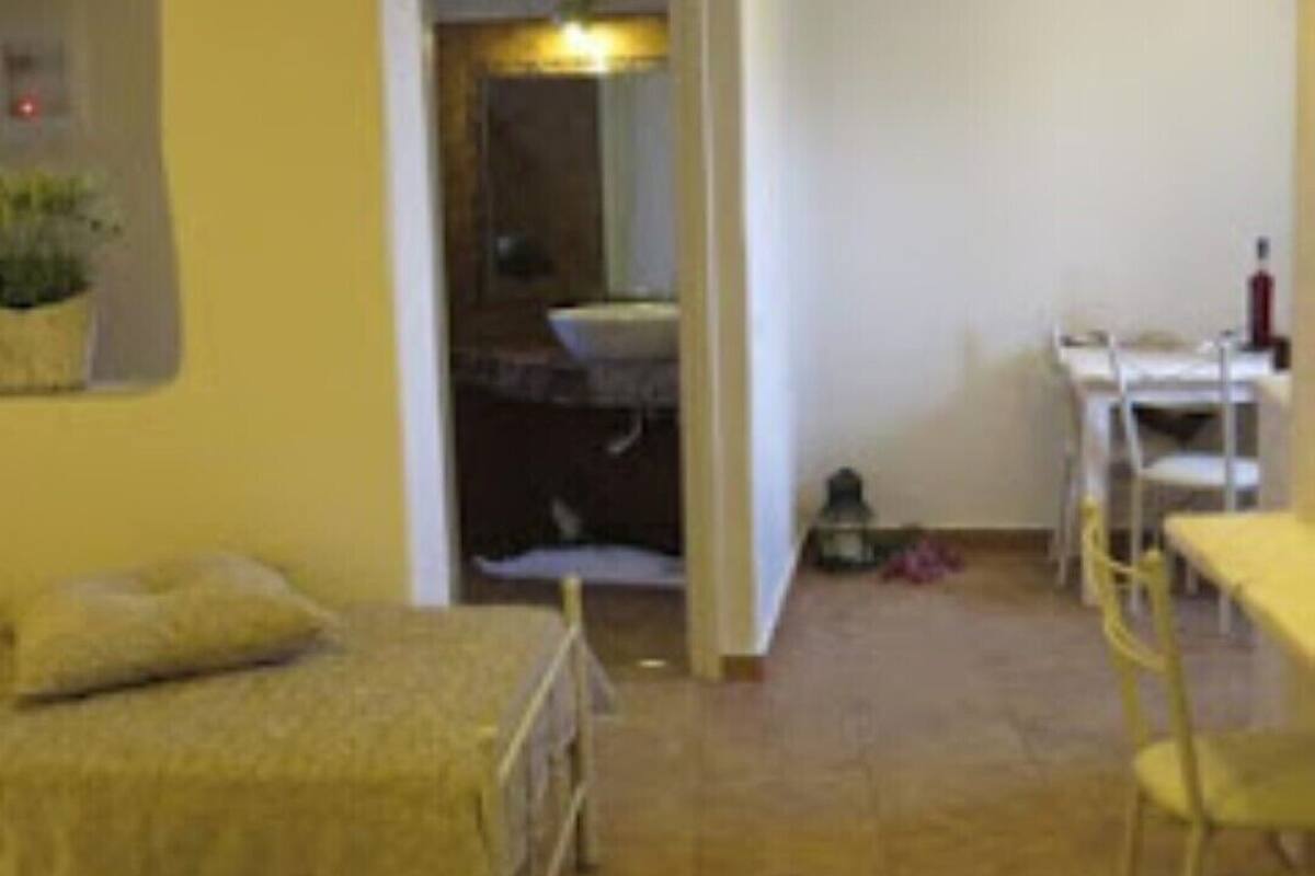 Una habitación con una cama, una mesita y una silla. Hay una puerta que da a otra habitación.