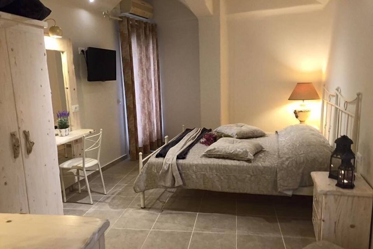 Un dormitorio con cama, mesita de noche, lámpara y un escritorio con silla.