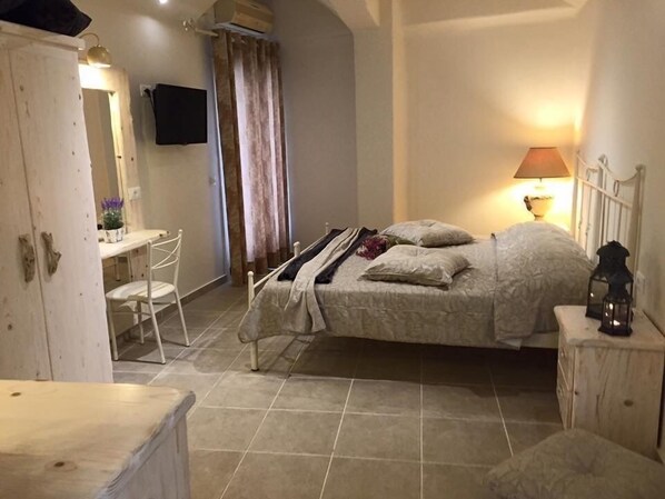 A bedroom with a bed, bedside table, lamp, and a desk with a chair.