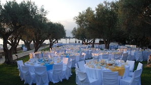 Un espacio para eventos al aire libre con mesas redondas cubiertas con manteles blancos y sillas, preparado para una reunión.