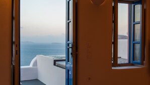 A room with a view of the sea, a balcony, and a blue-framed window. - Chroma Suites (Santorini)