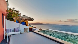 A poolside area with a view of the sea, a white table, and a blue door. - Chroma Suites (Santorini)