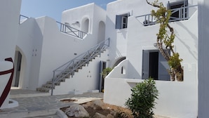 A white building with a staircase, a door, and a window. - Teoria Paros | Matsas Windmill (Paros)