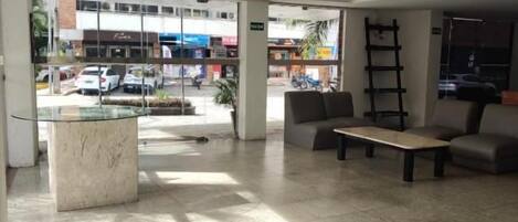 A spacious lobby with a glass coffee table, seating area, and a view of the street outside.