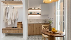 A modern kitchen with wooden cabinets, a built-in sink, and a dining area with a round table and chairs. - Pension Sofi (Naxos)