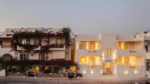 A modern two-story building with balconies, a sign indicating a restaurant, and warm interior lighting. - Pension Sofi (Naxos)