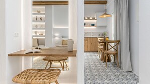 A modern kitchen with wooden cabinets, a dining area with a wooden table and chairs, and a patterned floor. - Pension Sofi (Naxos)