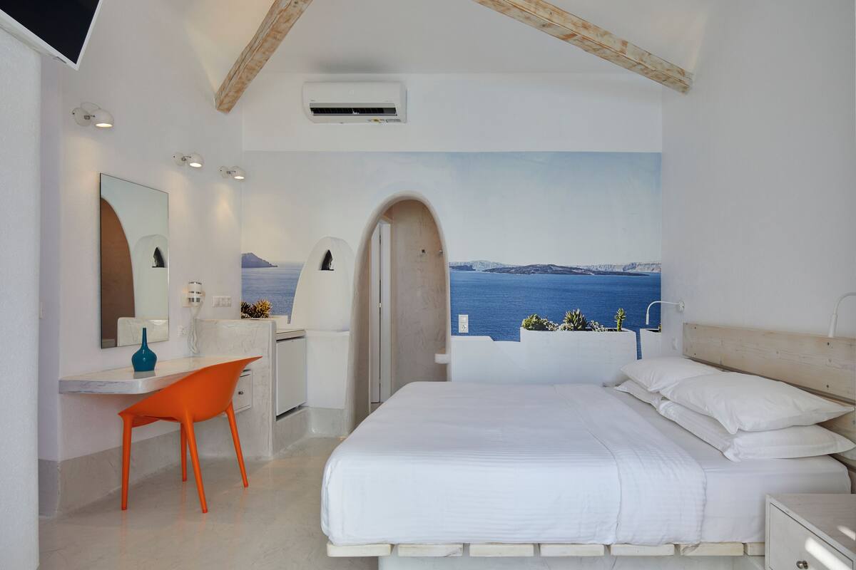 Un dormitorio con cama, escritorio, silla y vista al mar.