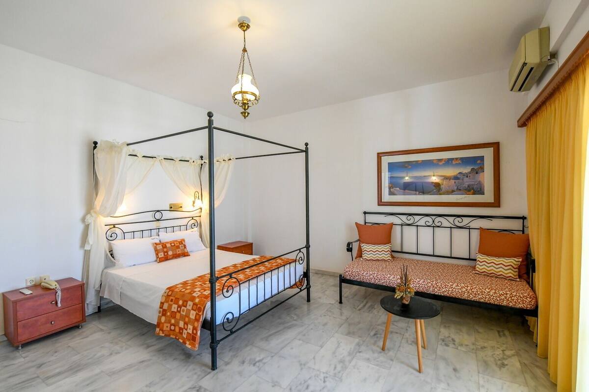 Ein Schlafzimmer mit einem Himmelbett, einem Sofa, einem Nachttisch und einem kleinen Tisch mit einer Vase.