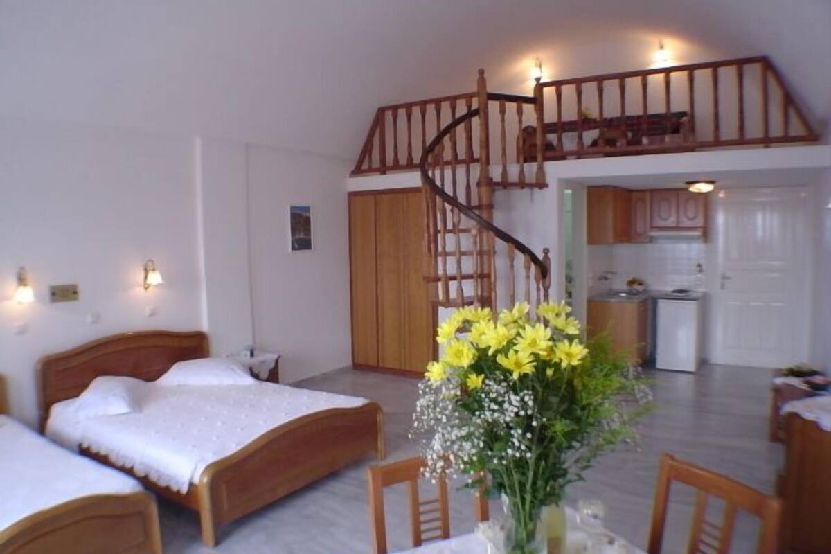 Ein Schlafzimmer mit zwei Betten, einer Treppe und einer Küche im Hintergrund.