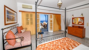 Un dormitorio con cama con dosel, cómoda, espejo y vista al mar a través de una puerta abierta.