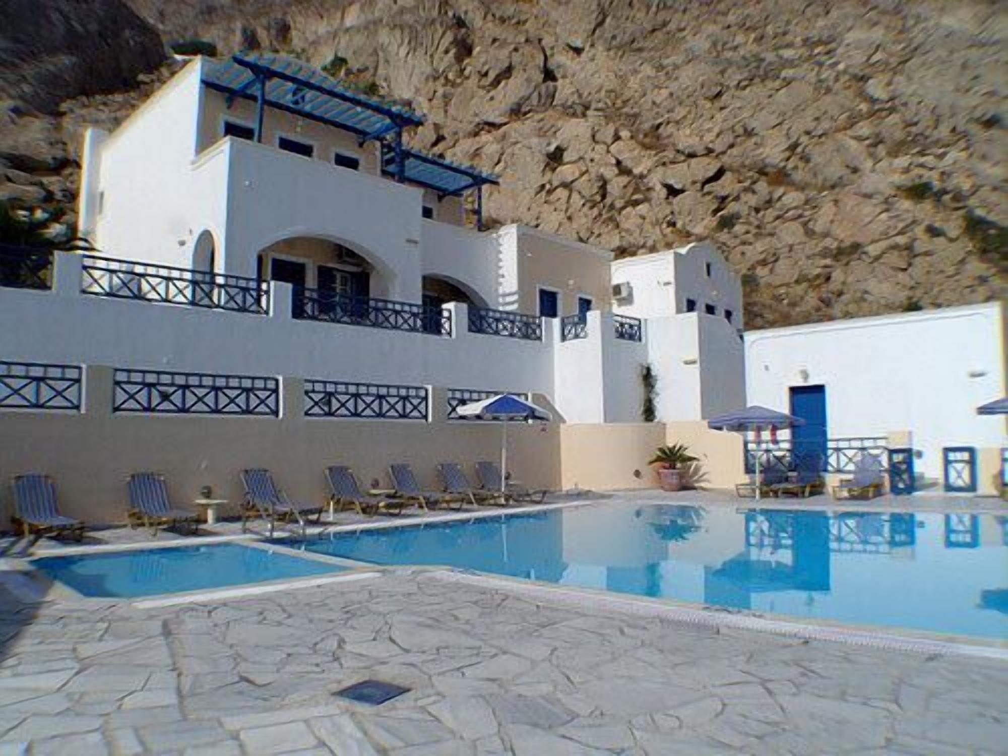 A hotel with a pool, outdoor seating, and a rocky cliff backdrop.