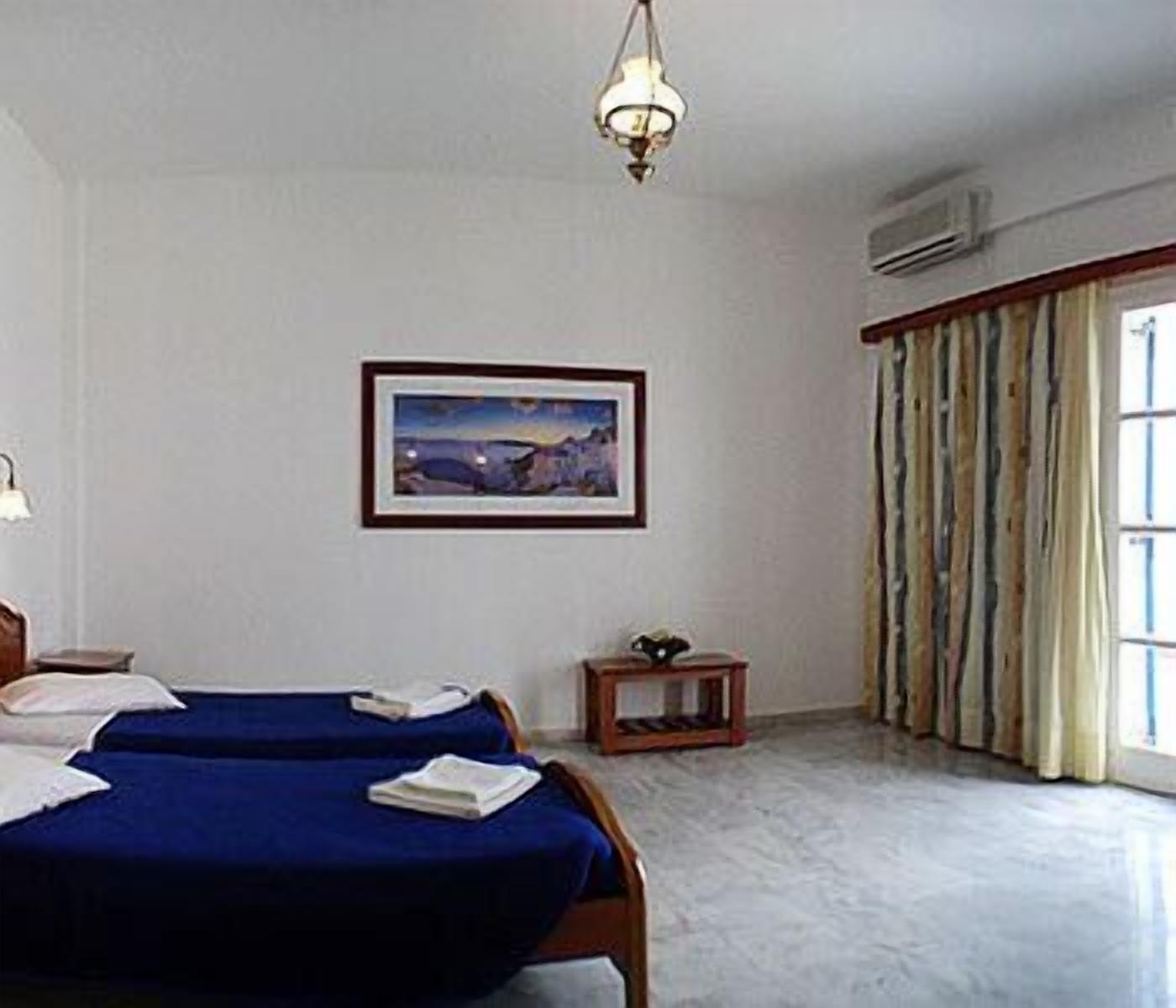 Une chambre d’hôtel avec deux lits, un tableau encadré au mur, une petite table et un appareil de climatisation.