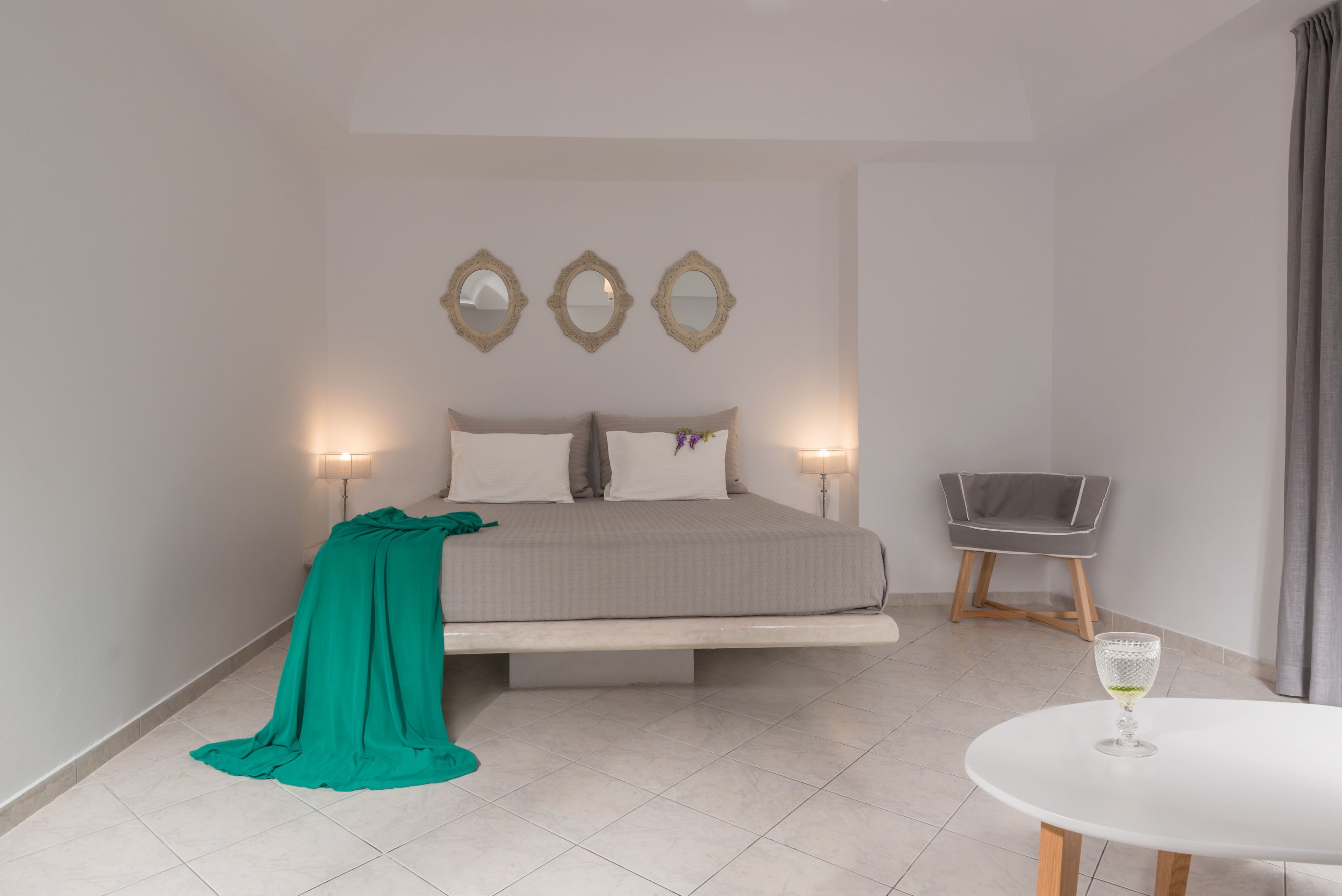 A bedroom with a bed, bedside lamps, a chair, and a table.