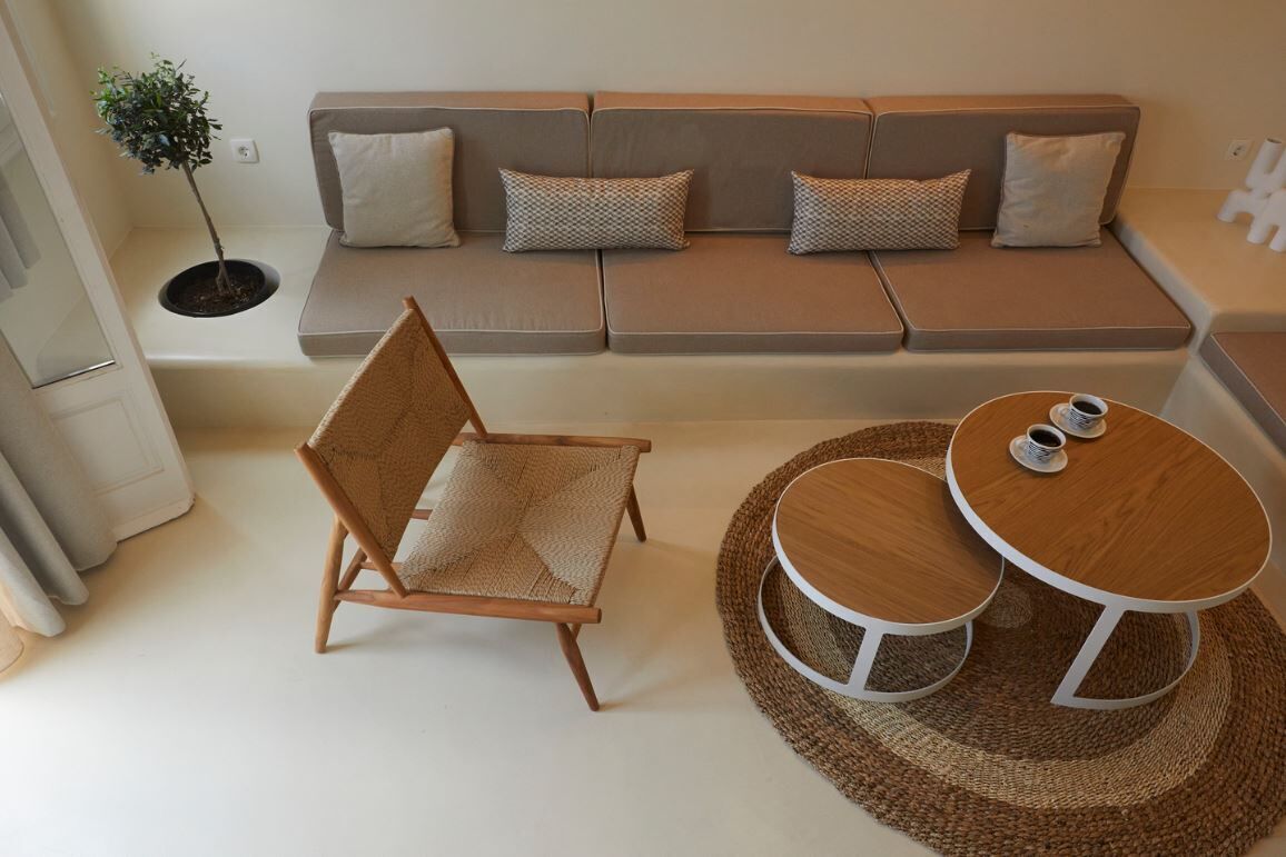 A modern living room with a sofa, a wooden chair, and a small round table with two cups.