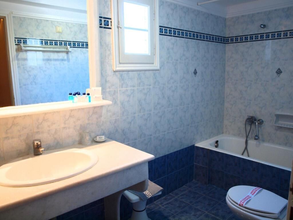 Un baño con lavamanos blanco, espejo, inodoro y bañera.
