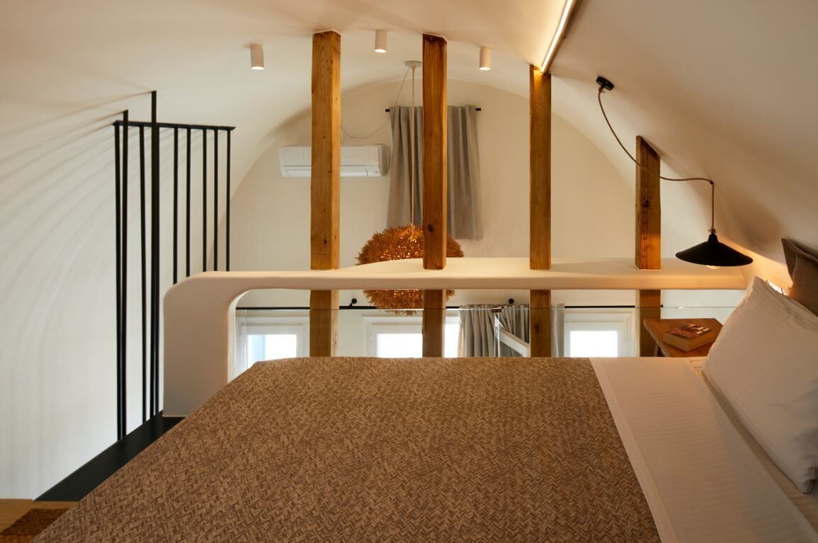 A bedroom with a bed, a hanging plant, and a desk with a lamp.