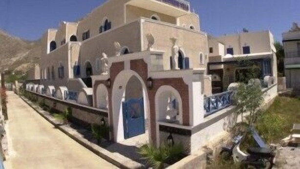 A two-story building with a flat roof, multiple windows, and a blue door. - Princess Santorini Villa (Santorini)