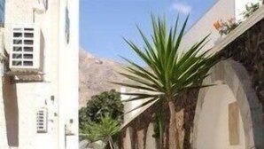A narrow, cobblestone street lined with white buildings featuring arched doorways and stone walls. - Princess Santorini Villa (Santorini)