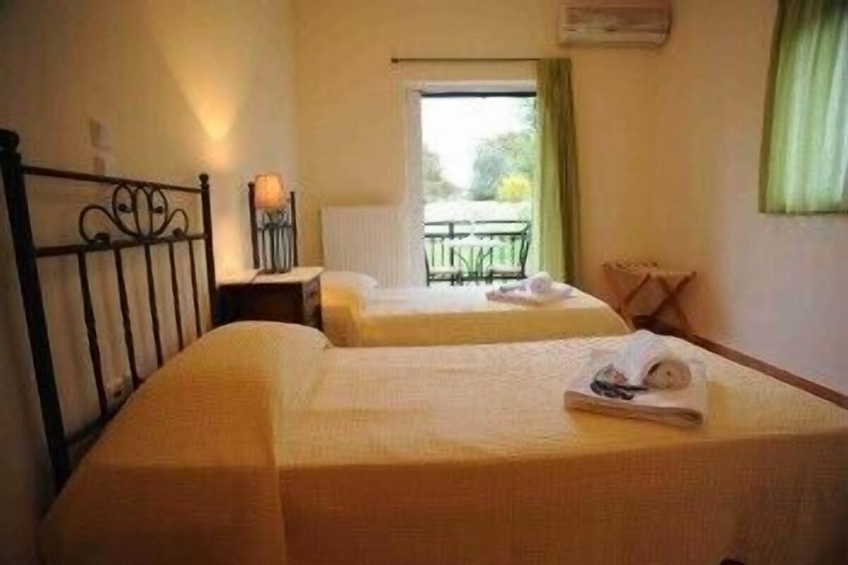 A hotel room with two beds, a window with a view, a small table, and a chair.
